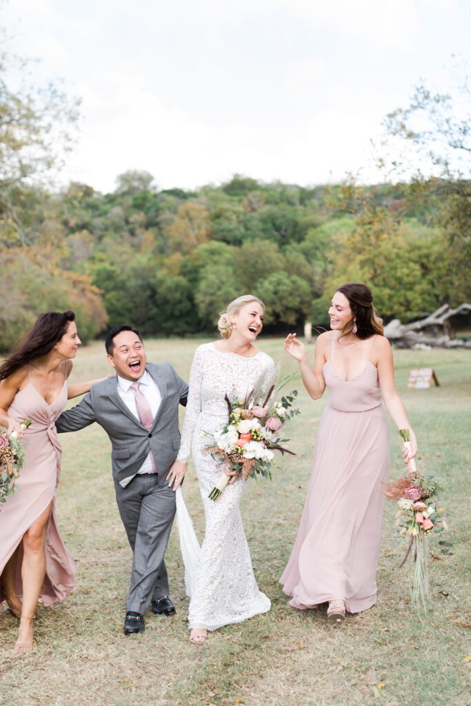 bride and bridesmaids groomsman laughing and walking in field