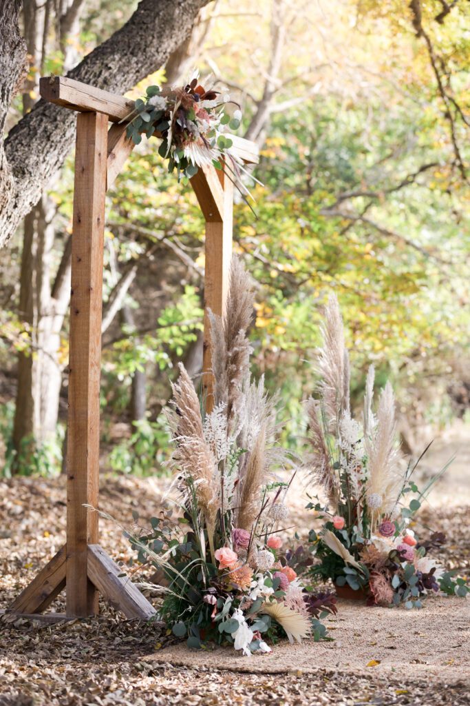 cedar wooden arbor with pampas grass and pale pink flowers