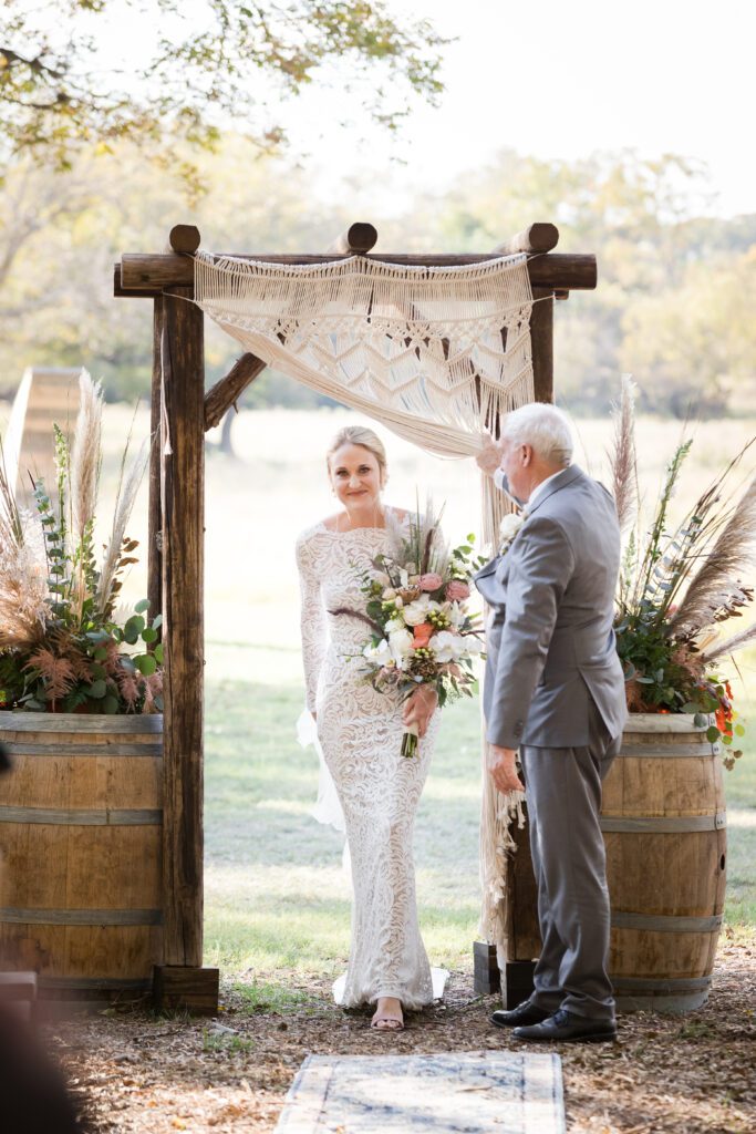 bride walking in through macrame curtain with her dad