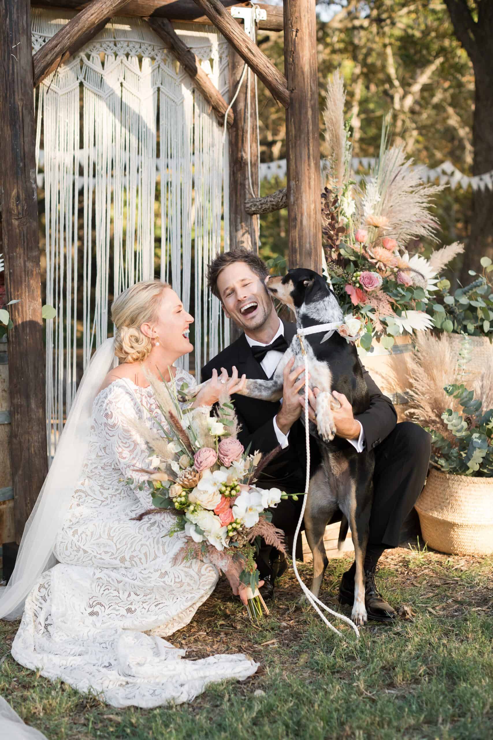 bride and groom laughing with their dog licking