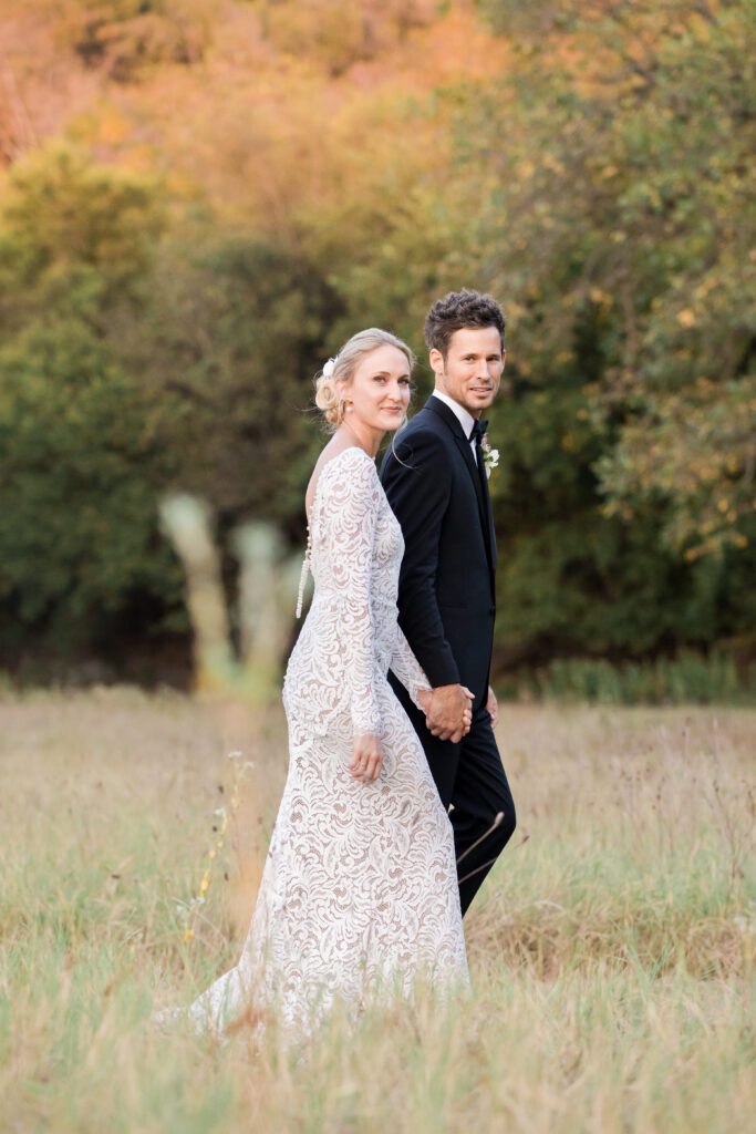 bride and groom walking in a field in the hill country