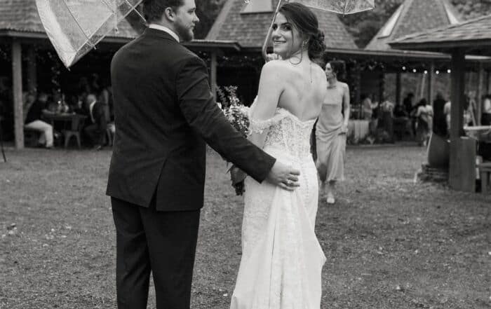Bride and groom with umbrellas at outdoor rainy wedding in Elm Pass Woods, Texas if you are Outdoor Wedding Planning Texas